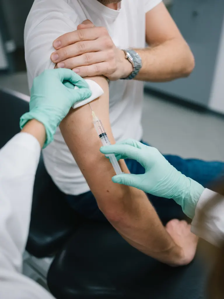 Reiseimpfungen & Beratung in München-Neuhausen – Hausarztpraxis am Romanplatz 2 Hausarzt in München Neuhausen verabreicht Impfung im Arm eines Patienten, symbolisiert umfassende Impfberatung und Expertise.