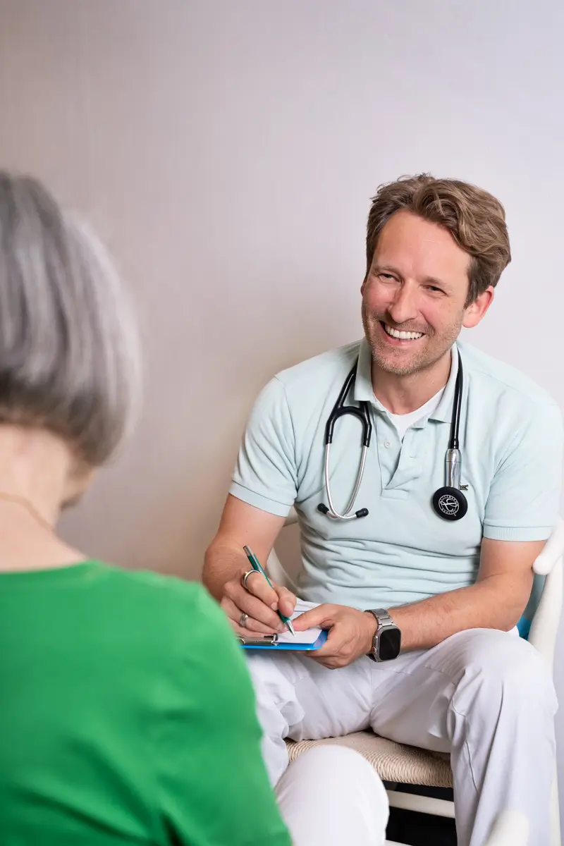 Hausarzt im Gespräch mit Patientin in der Hausarztpraxis am Romanplatz in München