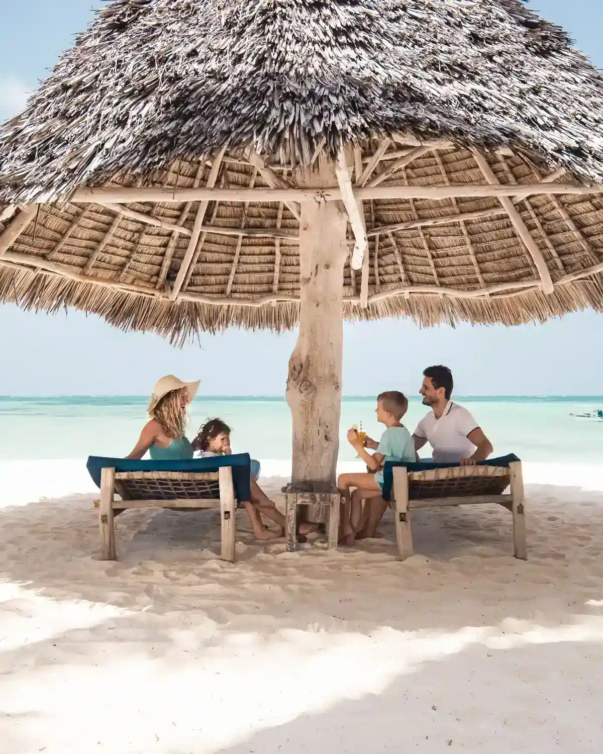 Familie im Strandurlaub unter Sonnenschirm, Ist Sonnencreme schädlich?, Vitamin D durch Sonnenlicht, Hautkrebs vermeiden durch Sonnenschutz, Sonnencreme und Lichtschutzfaktor im Alltag