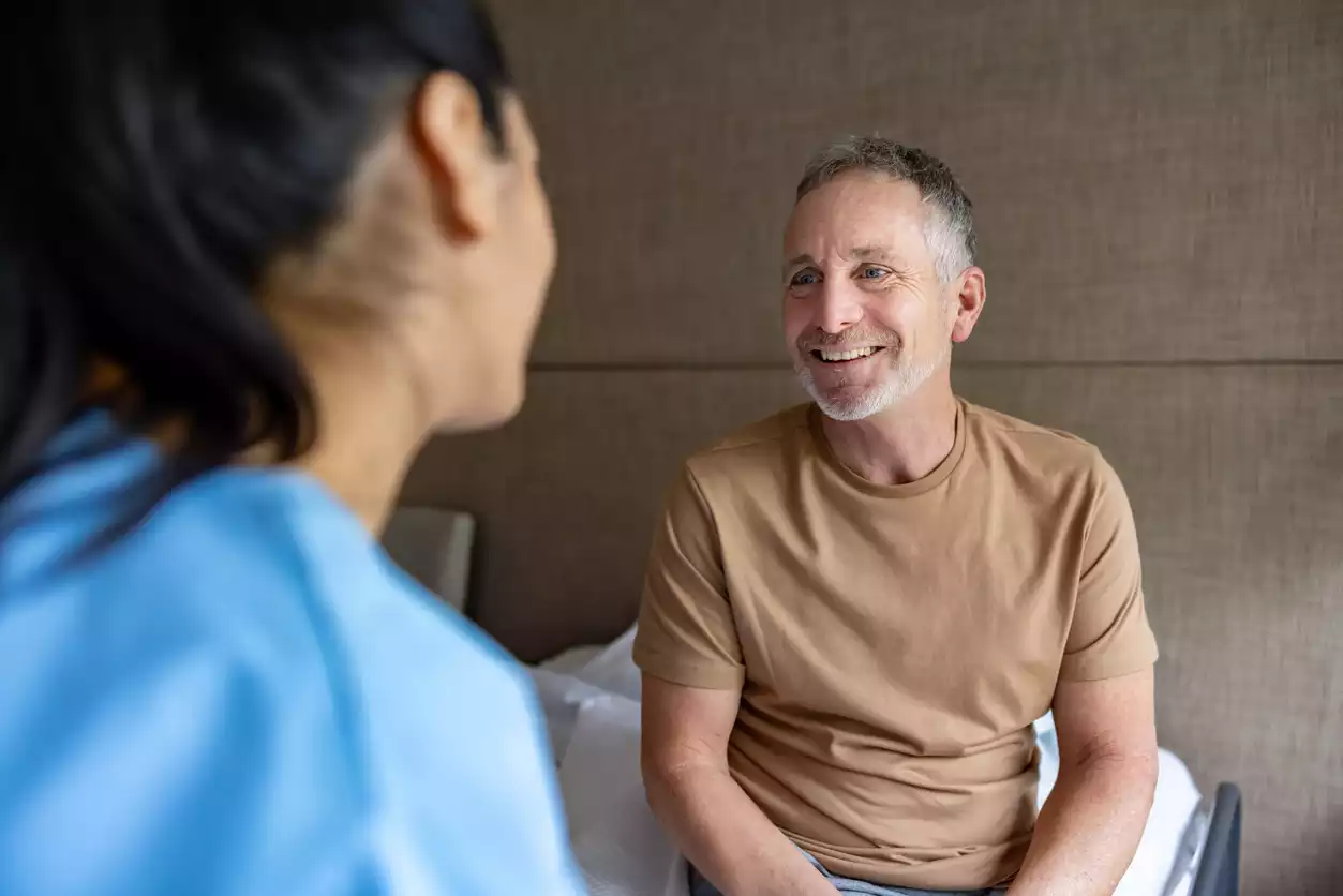 MFA der Hausarztpraxis am Romanplatz im Gespräch mit einem Patienten an der Anmeldung