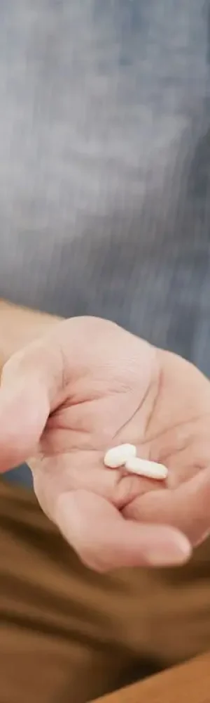 Closeup shot of an unrecognisable man holding a glass of water and medication in his hands